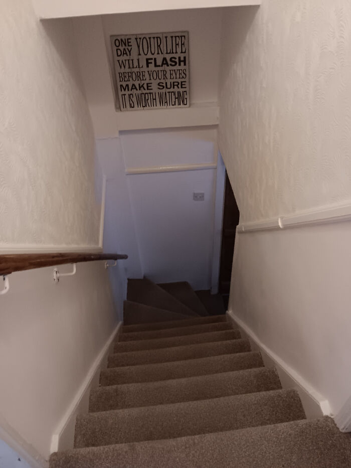 Narrow carpeted staircase with white walls and handrails, illustrating Airbnb insanity risk requiring insurance precautions.