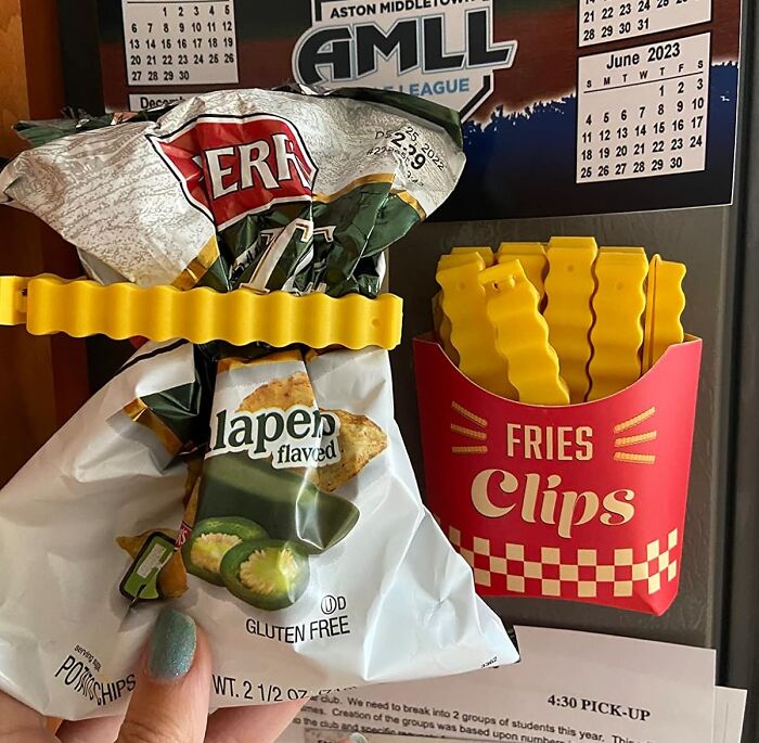 Yellow novelty fries-shaped clips sealing a chip bag on a refrigerator, showcasing unique novelty finds.