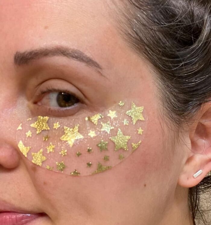 Close-up of woman's face with gold star novelty under-eye patch, an unnecessary novelty find trending for fun skincare.