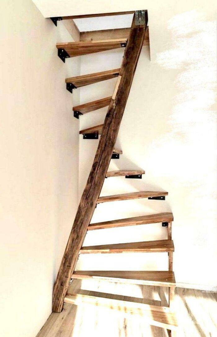 Narrow wooden spiral stairs with minimal supports in a bright room illustrating Airbnb stairs insurance risks.
