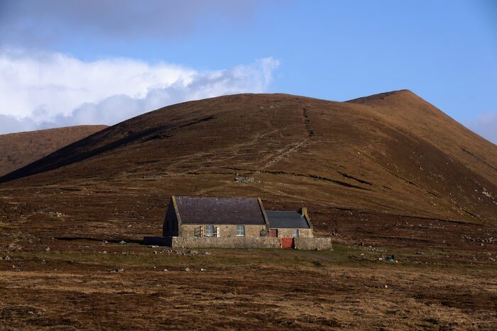 Stone house isolated at the base of a large barren hill, a remote location showcasing mind-blowing natural solitude and landscape.