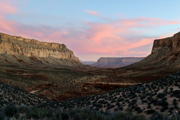 Vast remote desert landscape with rocky cliffs and a colorful sunset sky in an isolated location.