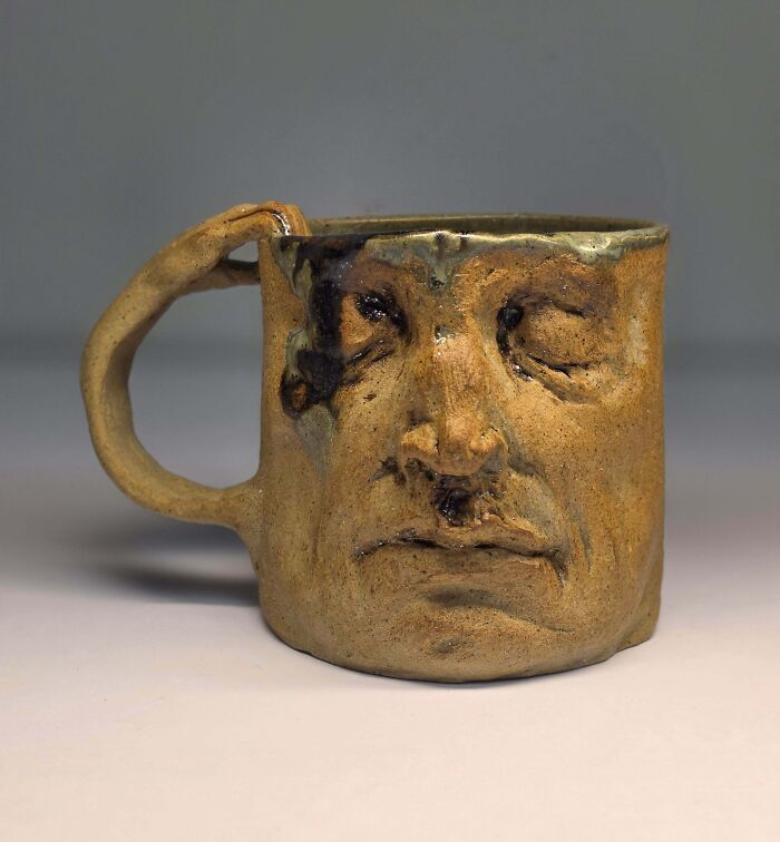Rustic ceramic mug with a detailed human face design, showcasing creative people and their cool art projects.