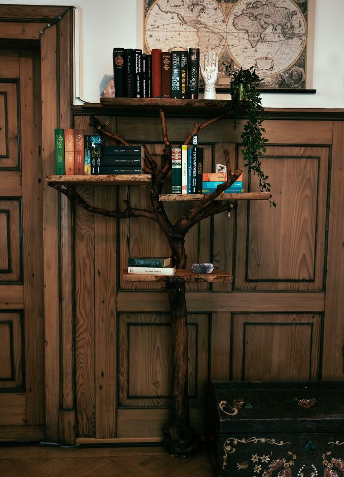 Creative tree-shaped bookshelf with books and plants, showcasing unique projects by creative people in an artistic home setting.