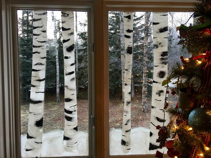 Winter scene with creative painted birch trees on window panes, showcasing cool projects by creative people indoors.
