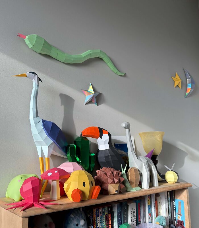 Colorful paper sculptures of animals and objects displayed on a shelf representing creative people projects and unique designs.