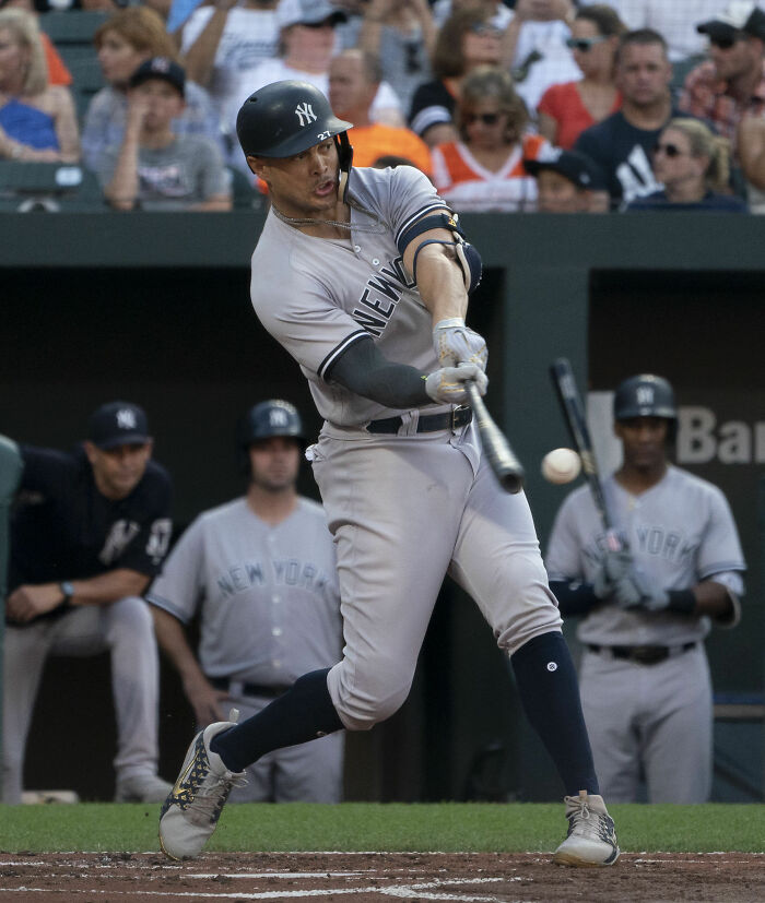 Giancarlo Stanton of the New York Yankees swinging a bat during a baseball game with spectators in the background