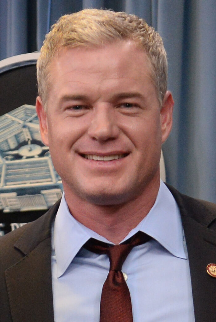 Eric Dane smiling, wearing a dark suit and tie, showcasing a career highlight moment in a formal setting.
