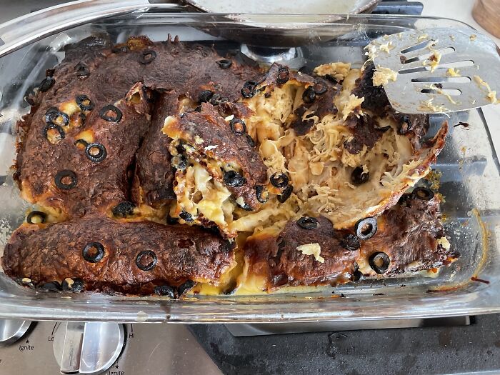 Burnt casserole with melted cheese and olives in a glass baking dish, showing a family cooking fail that caused frustration.
