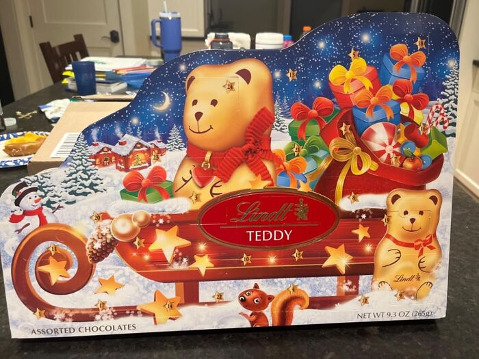 Colorful Christmas-themed advent calendar featuring a teddy bear and assorted chocolates for holiday countdown fun.