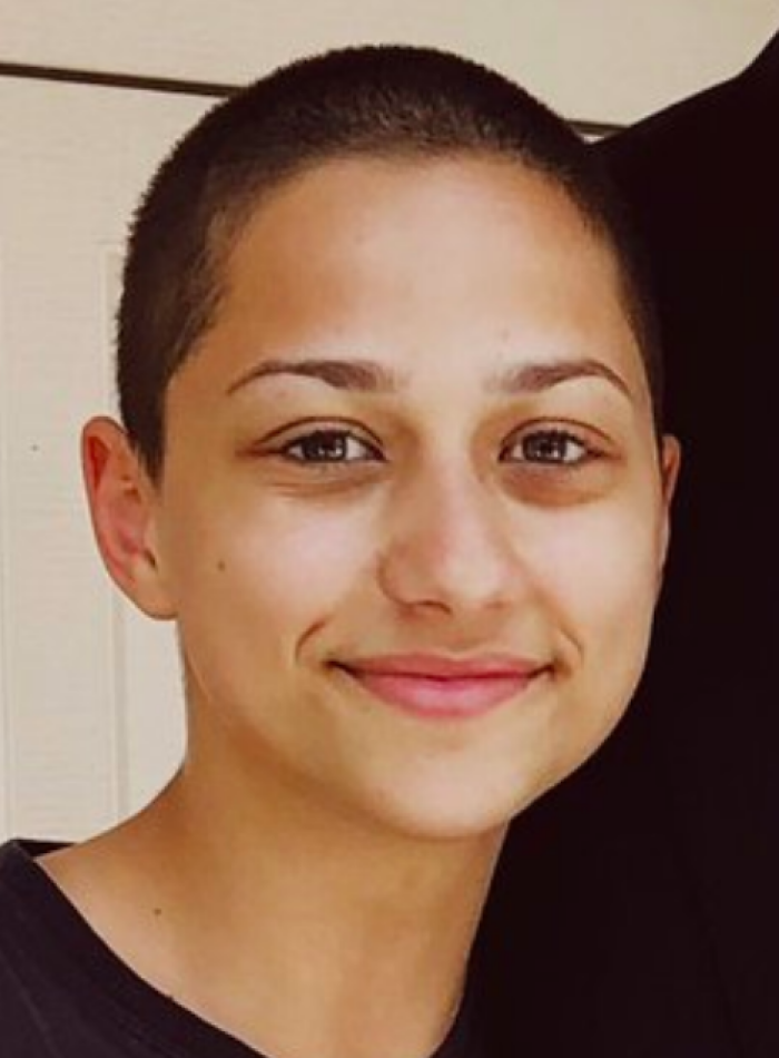 Close-up of X González smiling with a shaved head, showcasing a natural and confident look for bio and career highlights.
