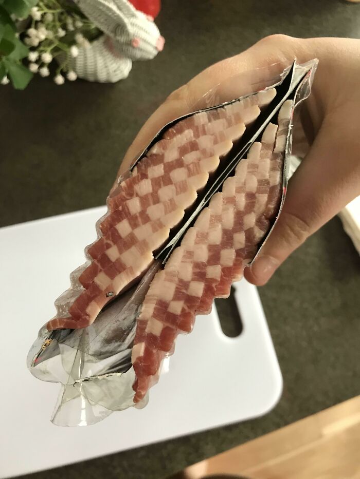 Hand holding a sliced bacon package showing the unexpected insides of the object for inside objects new pics SEO.