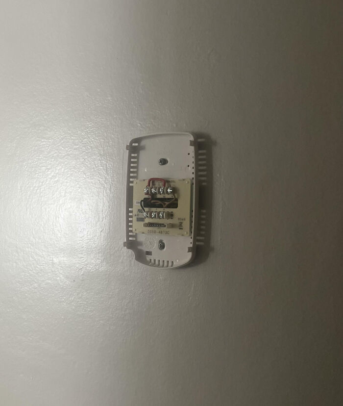 Thermostat cover removed from wall, exposing internal wiring, illustrating frustration with family members in a vent online post.