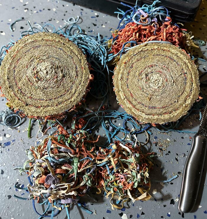 Cross-section of a rolled-up ballpoint pen ink refill showing colorful shredded paper inside with a cutting tool nearby.