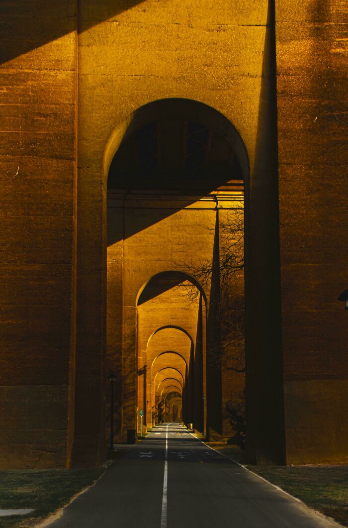 Underneath large concrete arches, a road leads into the distance, showcasing an amazing perspective of the world.