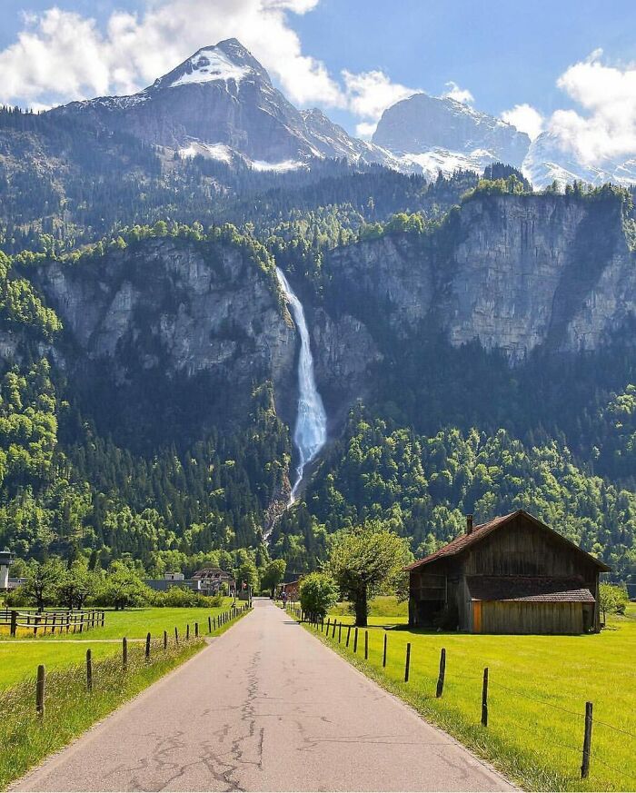 Scenic mountain landscape with waterfall and rural road showcasing our world from a different perspective.