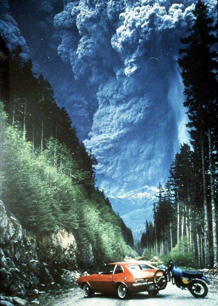 Volcanic eruption captured from a low angle with a road, car, and motorcycle showing our world from a different perspective.