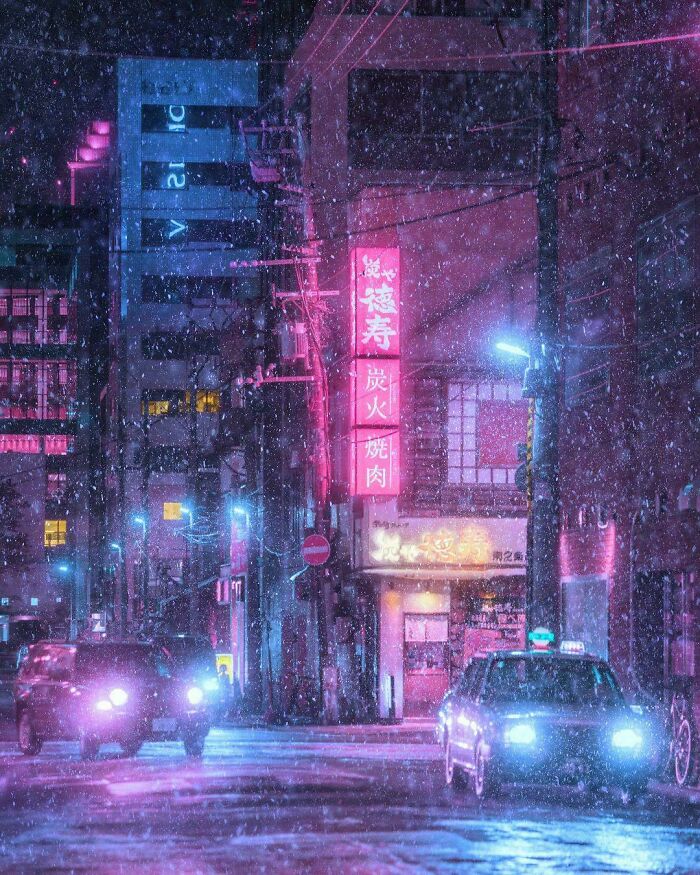 City street at night with cars and neon signs during snowfall, showing our world from a completely different perspective.