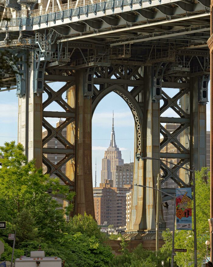 View of the Empire State Building framed by bridge steel beams, showcasing a unique new perspective of the world’s architecture.