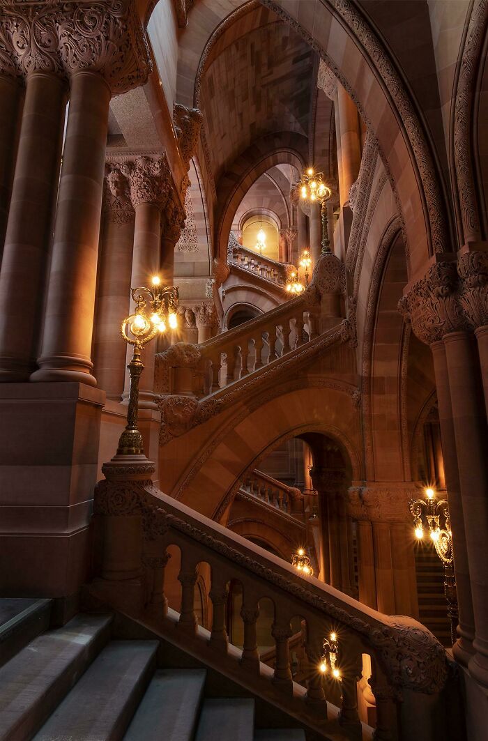 Ornate staircase with glowing lamps and intricate carvings, showcasing amazing pics of our world from different perspectives.