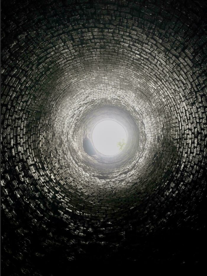 View inside an old brick well showing light at the top, illustrating a unique perspective of our world.