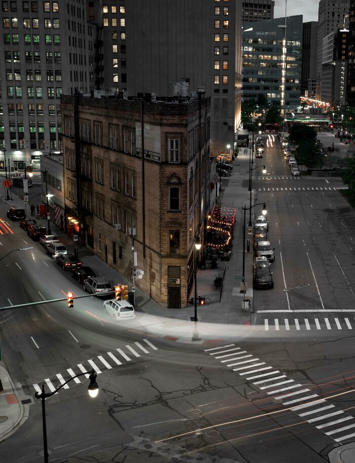 A triangular building at a city intersection captured at night showing a unique perspective of urban architecture.