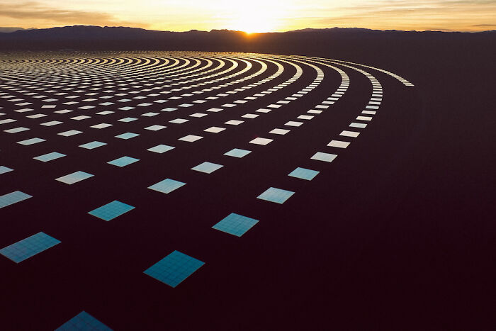 Aerial view of solar panels arranged in curved patterns at sunset showing our world from a different perspective