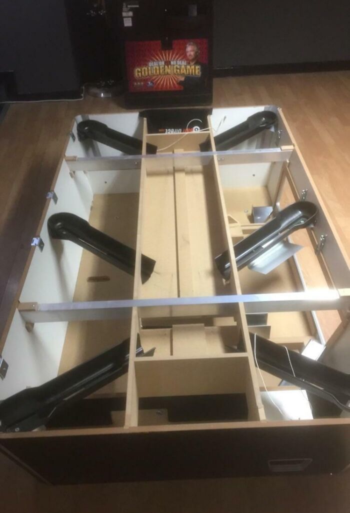 Inside view of an object showing structural components and black angled supports in a wooden frame assembly.