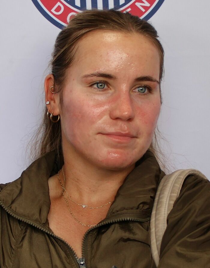 Sofia Kenin with light brown hair and earrings, wearing a brown jacket, captured in a casual setting indoors.
