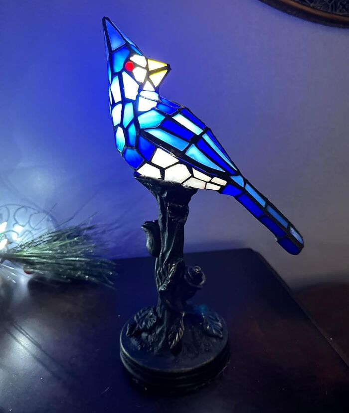 Stained glass blue bird lamp glowing on a table, a unique gift idea for holiday shopping satisfaction.