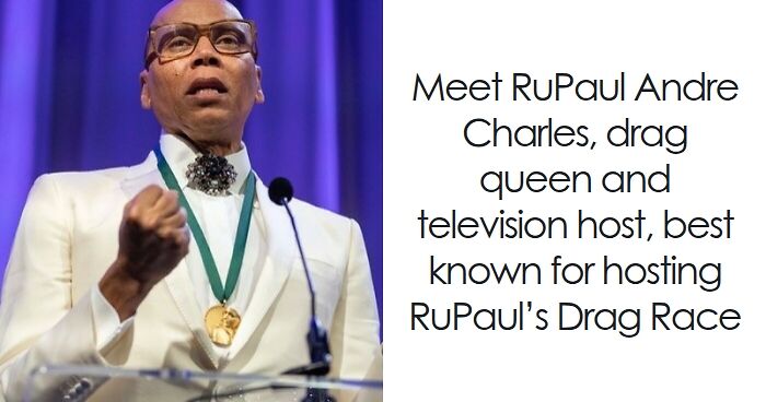 RuPaul wearing a white suit and glasses, speaking at a podium with a medal around his neck.