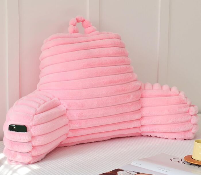 Pink plush backrest pillow with armrests and a phone holder, a cozy find to make your house feel warm and inviting.
