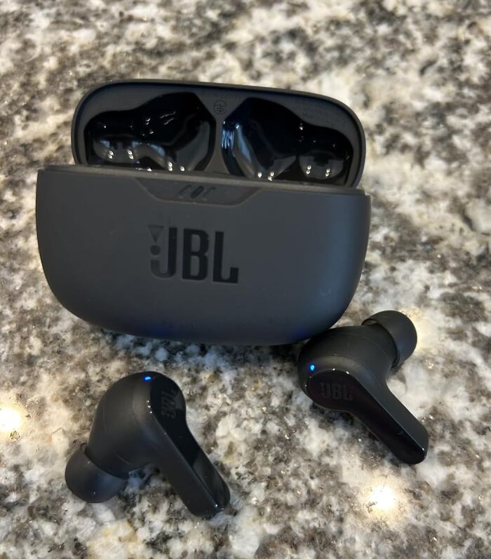 JBL wireless earbuds with charging case on a granite surface, featured in Black Friday deals to add to wishlist.