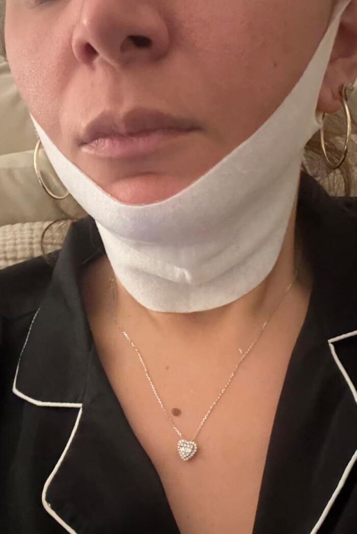 Woman wearing a white chin lifting mask and heart-shaped necklace, showcasing a Black Friday deal to add to your wishlist.