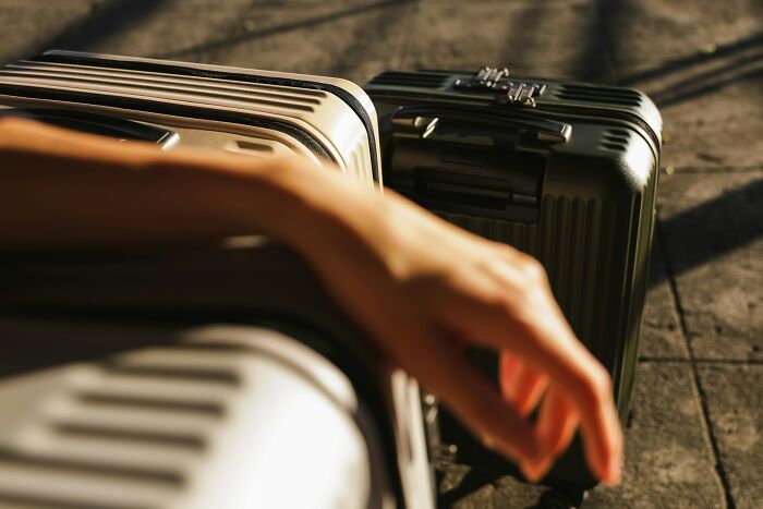 Suitcases on the ground with a person's hand resting on one, symbolizing refusal to move in after boyfriend secretly testing them.