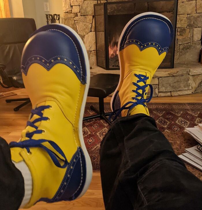 Colorful blue and yellow shoes worn by a person relaxing indoors by a stone fireplace, inspiring creative dreams realized.