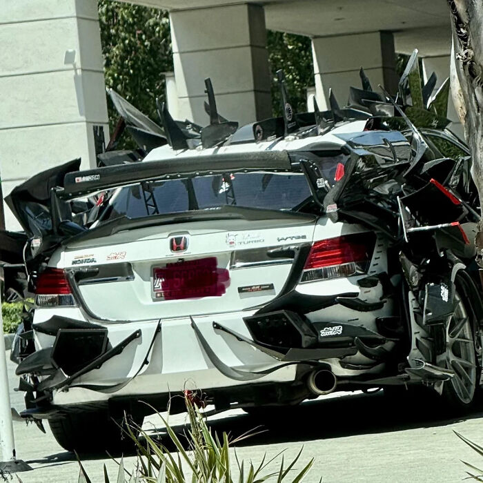 Honda car with excessive aftermarket parts and wing attachments, showcasing an extreme and confusing attempt to make the car cooler.