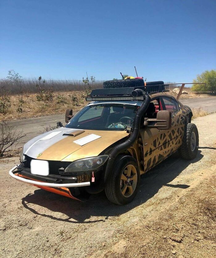 Modified car with off-road tires, roof rack, and unusual vent pipe, an example of stupidity on wheels customization.