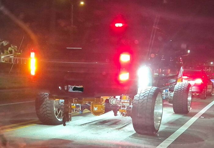Pickup truck with overly large wheels and bright underglow lights, an example of failed car customization.