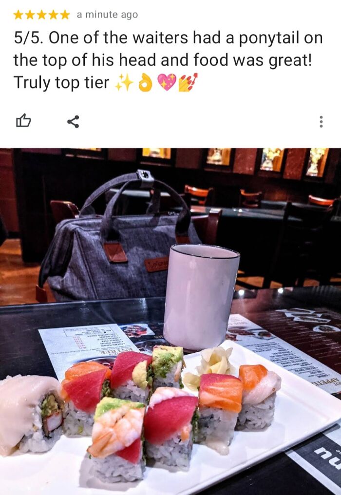 Hilariously unhinged review praising sushi restaurant with colorful sushi rolls and a white cup on a table inside a dim dining area.