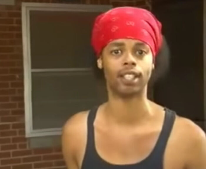 Man wearing red bandana and black tank top, captured in a viral moment becoming an internet icon randomly.