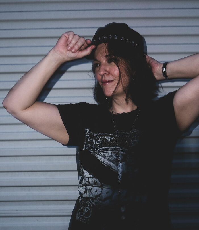 Woman wearing a black hat and graphic t-shirt, smiling confidently and inspiring with dreams turned into reality.