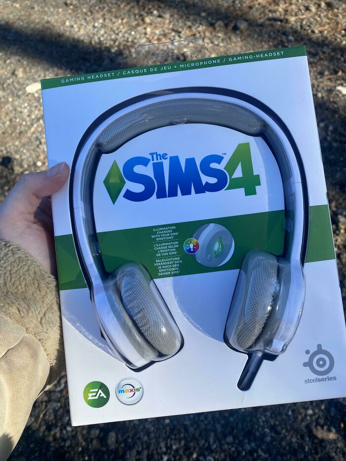 Person holding The Sims 4 gaming headset package outdoors, showcasing the design and branding of the gaming accessory.