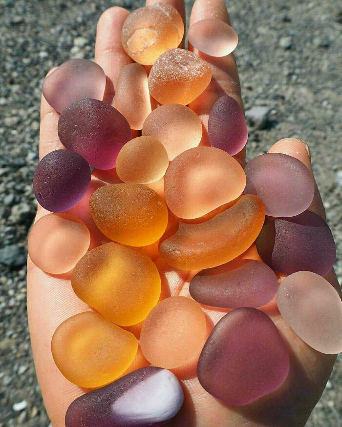Smooth, translucent, multicolored stones resting on a hand, resembling forbidden foods to resist for your own good.