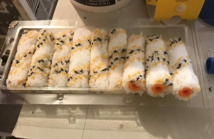 Plastic tray holding multiple sushi rolls with rice, seaweed, and orange filling, illustrating forbidden foods concept.
