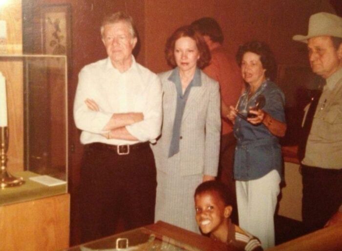 Young boy photobombs serious group photo with a big smile, creating an epic photobomb that made everyone laugh.