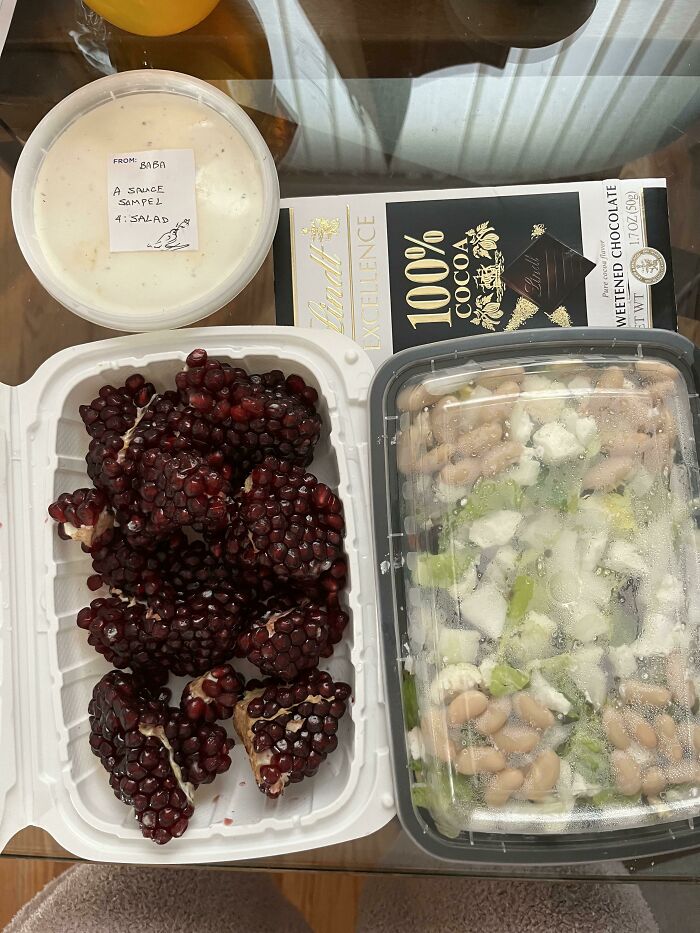Wholesome internet moment showing a salad, pomegranate seeds, sauce sample, and dark chocolate on a table.