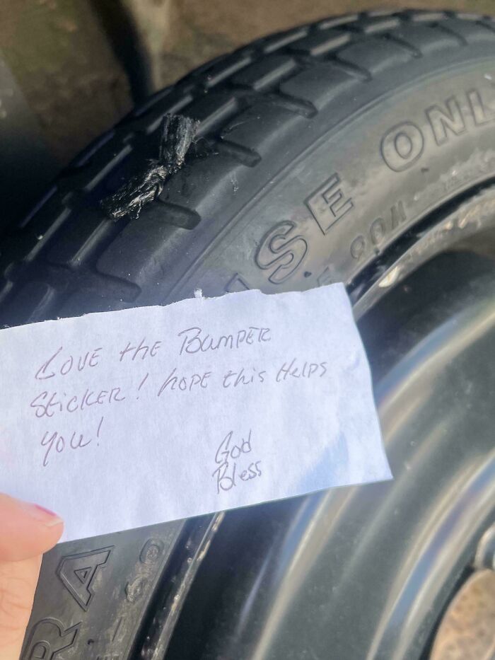 A close-up of a tire with a handwritten note offering help, showing wholesome internet moments online.