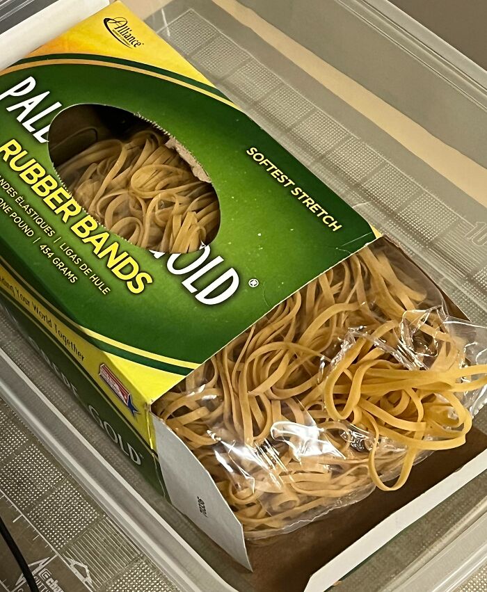 Pack of yellow rubber bands inside a partially opened box sitting in a plastic container, illustrating forbidden foods concept.