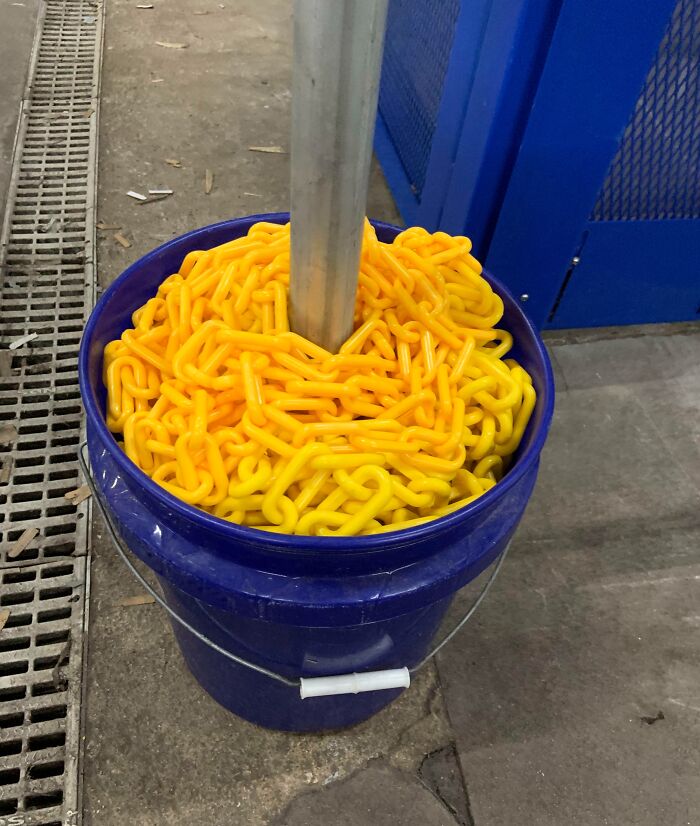 Bright yellow plastic chains coiled inside a blue bucket, illustrating a concept of forbidden foods warning.